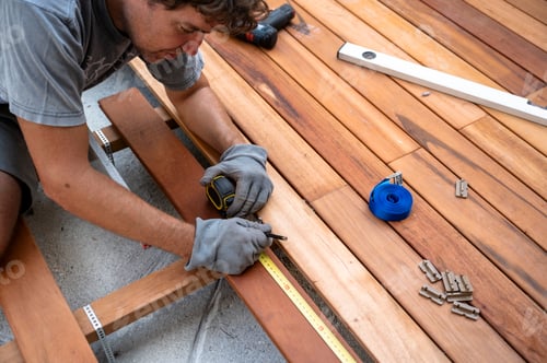 Preview: Skilled worker installing wooden deck