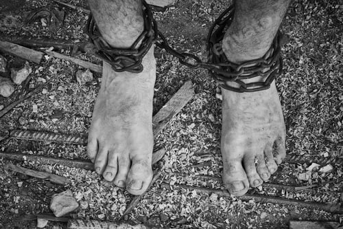 Preview: Close-up shot of barefoot legs tied up with old chain