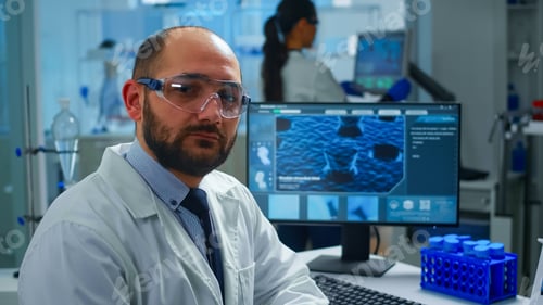 Preview: Portrait of exhausted scientist man looking at camera sitting in front of computer