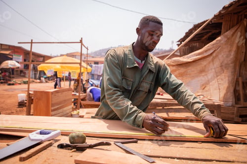 Preview: An african carpenter taking measurements while making a piece of furniture
