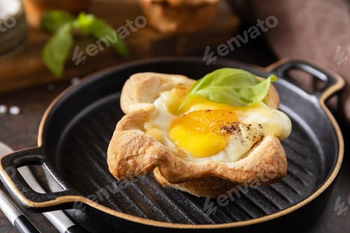 Preview: Scrambled eggs in puff pastry with cheese and bacon on a stone plate. Breakfast idea, snack foods.