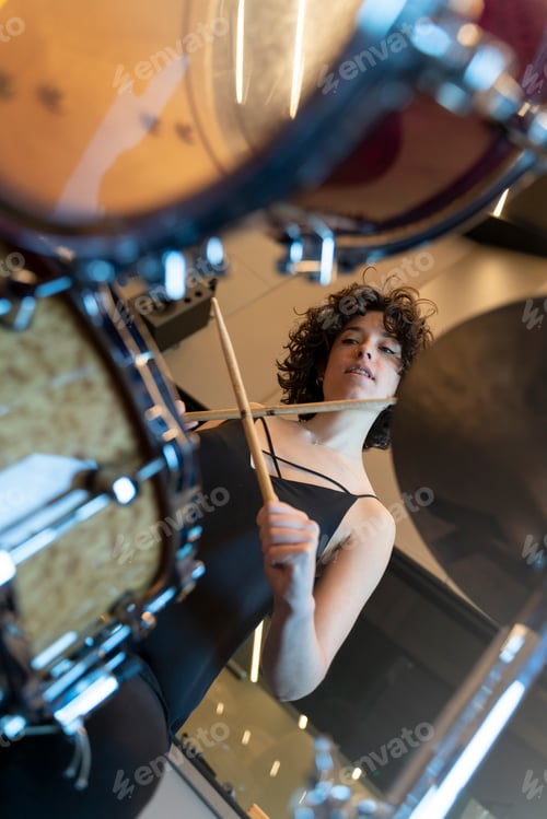 Preview: Young woman with curly hair playing the drums in a recording studio