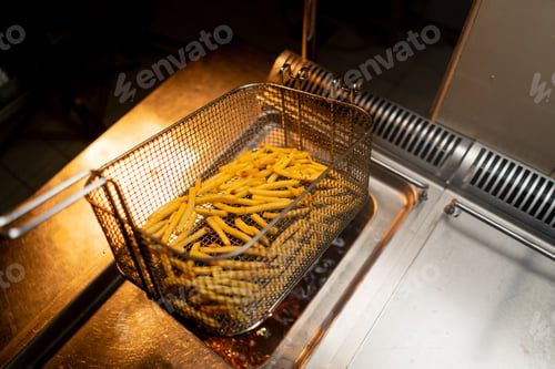 Preview: professional kitchen in hotel restaurant, the chef takes out delicious french fries from the fryer