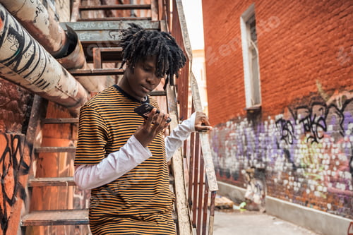 Aperçu: Portrait of young handsome stylish black man with natural hair dreadlocks. Afroamerican guy. Stairs,