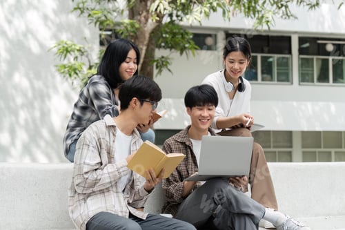 Preview: University students sitting together at table with books and laptop and tablet. Happy young people