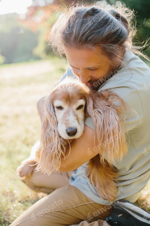 Preview: Man embracing his cute dog in a sunny park