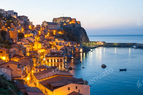 Preview: Picturesque coastal town at dusk, with illuminated castle on cliff.