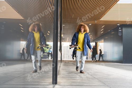 Preview: Young man walking with skateboard in urban setting