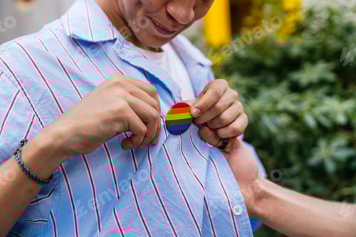 Preview: Person Putting on Rainbow Pride Button On Shirt