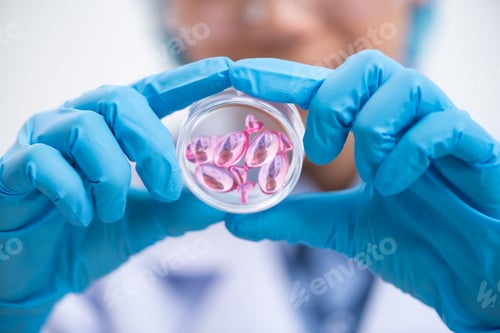 Preview: Young attractive female scientist with protective eyeglasses and mask holding