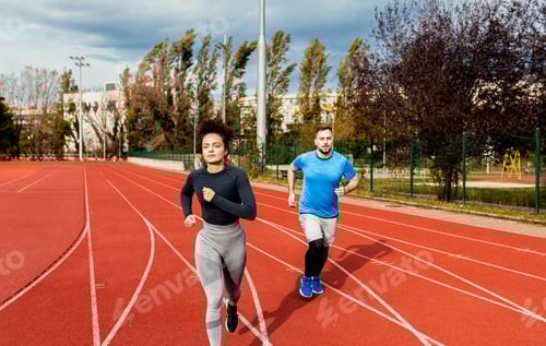 Preview: Woman and man doing morning workout outdoors running on track.