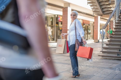 Preview: Mature woman shopper waiting for friend in shopping mall