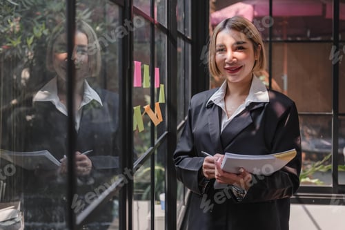 Preview: Young businesswoman creative team using post it notes in glass wall to writing strategy business