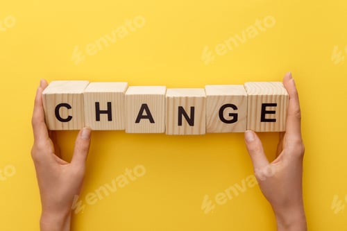 Preview: cropped view of woman holding wooden cubes with change inscription on yellow background
