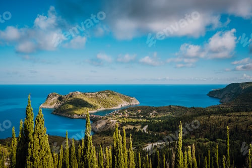 Preview: View to Assos village in sun light and beautiful blue sea. Green cypress trees in foreground