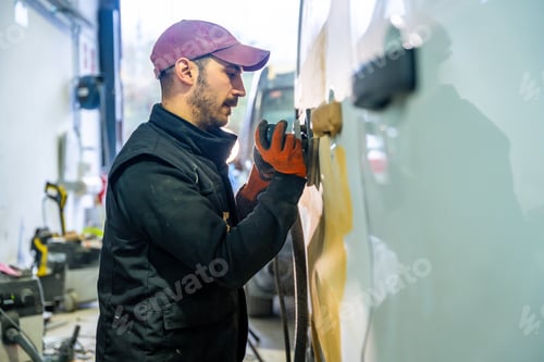 Preview: Auto body technician sanding car panel for repair