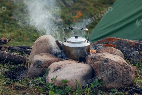 Preview: in a camping metal kettle, picnic water is boiled on a campfire