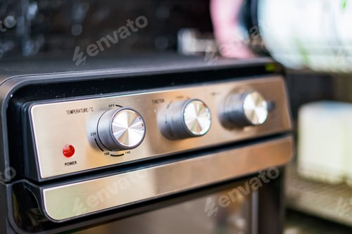 Preview: Hand turning temperature knob on the modern air fryer oven.
