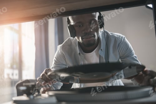 Preview: African american man playing vinyl record at home