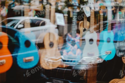 Preview: Music in the city. Bright and colorful guitars hanging in row in the shop window behind the glass
