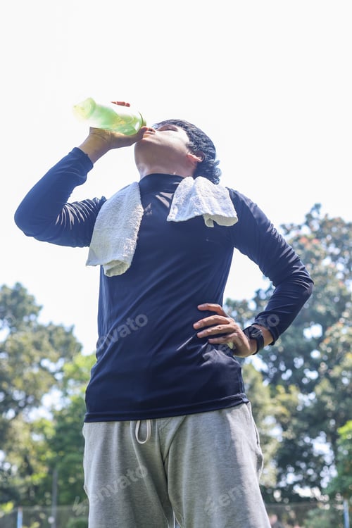 Preview: Young sportsman drinking water after workout outdoor