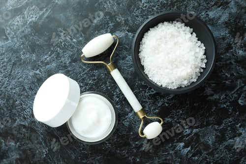 Vista previa: Skin care concept with face roller on black smokey table
