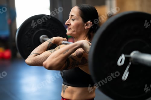 Preview: Sportive strong woman doing an effort to lift weights
