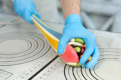 Preview: Close-up of the chef's hands, which stretches caramel, lollipops with a spatula pattern. Candy.