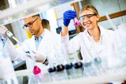 Preview: Young female scientist examining liquid in biochemical lab