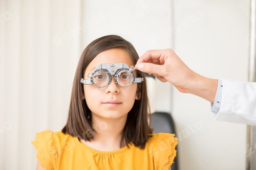 Preview: Oculist and little girl with trial frame in clinic