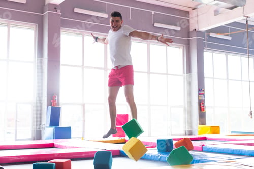 Preview: Fitness, fun, leisure and sport activity concept - Handsome happy man jumping on a trampoline