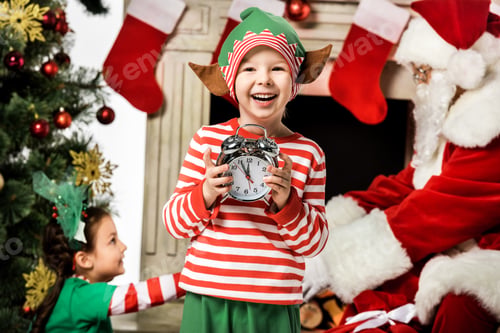Preview: adorable little kid holding alarm clock with his sister and santa passing gift box on background