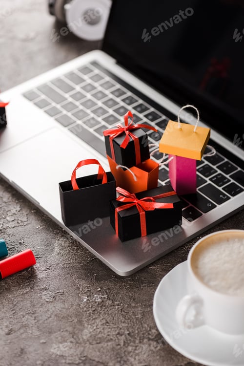 Preview: selective focus of shopping bags near laptop, cup of coffee and marker pens, e-commerce concept