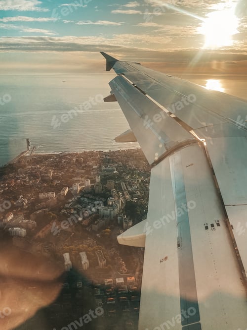 Preview: Wing of a plane flying over a city