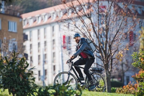 Preview: Male courier with electric bicycle delivering packages in city.