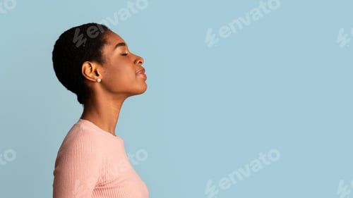 Preview: Profile Of Young African-American Woman Standing With Closed Eyes Over Blue Background