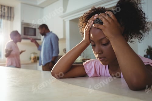 Preview: Sad girl listening to her parents arguing in kitchen