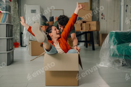 Preview: Couple having fun while moving into new home with cardboard box