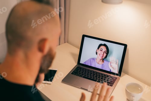 Preview: Man facetime at home, calling his friend wife girlfriend from laptop in bedroom.