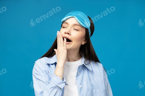 Preview: Young woman in a sleeping mask on a blue background