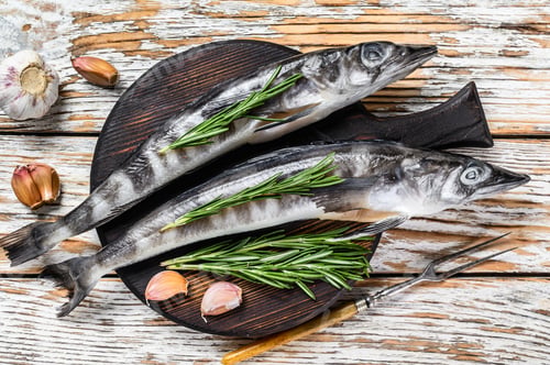 Preview: Raw whole icefish with herbs. White Wooden background. Top view