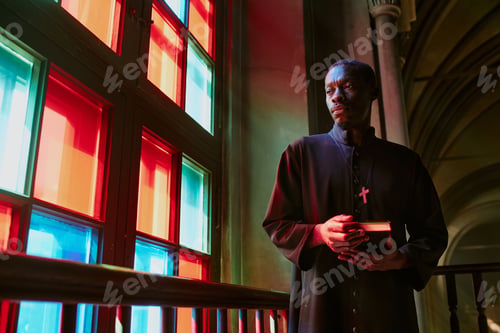 Preview: Priest with Bible in Hands Standing Next to Window