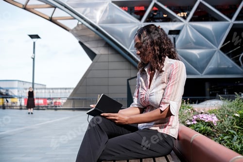 Preview: Black business woman writing on a notebook.