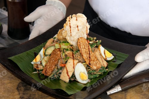Preview: Ready dish served on a plate in the cook’s hands. Indonesia Bali food