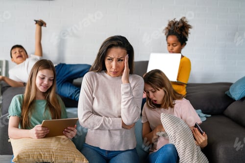 Preview: Sad woman with multiethnic children using digital gadgets.. Family and modern technology addiction.
