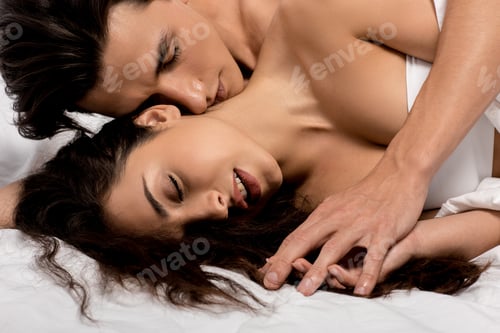 Preview: top view of passionate man hugging girlfriend and lying on white bed