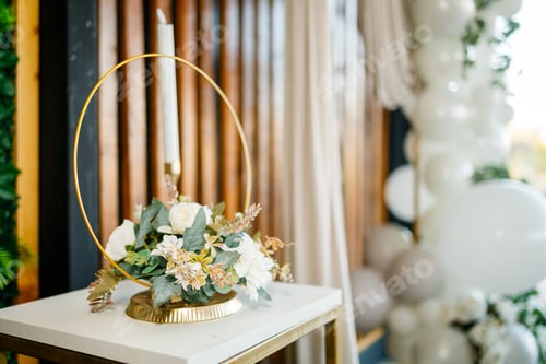 Preview: Centerpiece with white flowers and candle on a table at a celebration in daylight
