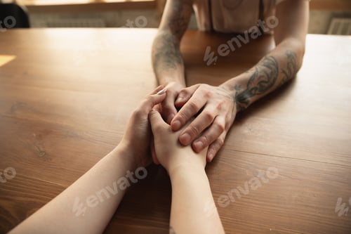Preview: Loving couple holding hands close-up on wooden background, romantic