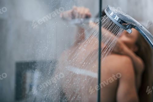 Visualização: Vista através do vidro de um jovem casal que se abraça e se beija no banheiro