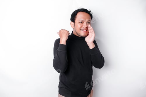 Preview: Excited Asian man wearing black shirt pointing at the copy space beside him.